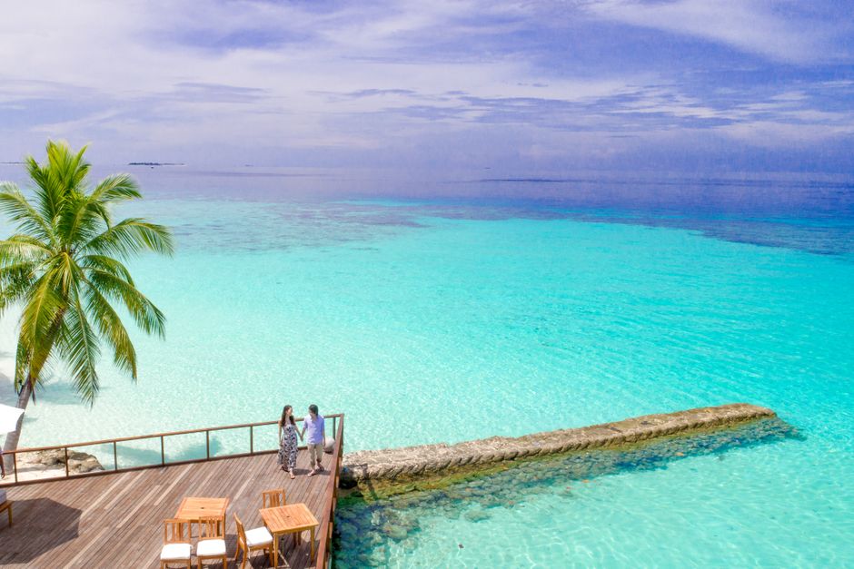 Couple enjoying a peaceful moment on a tropical deck overlooking the turquoise waters of the Maldives.